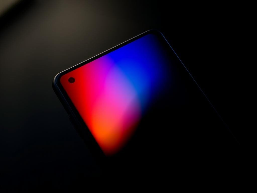High-resolution close-up display of the Samsung Galaxy S25 Ultra smartphone, showcasing its vibrant, high-contrast OLED screen with deep blacks and vivid colors. The display is illuminated from the side, creating a dramatic interplay of light and shadow that emphasizes the screen's quality and clarity. The phone is captured at a slight angle, allowing the viewer to appreciate the sleek, premium design and attention to detail. The background is blurred, placing the focus entirely on the exquisite display and its outstanding visual performance.